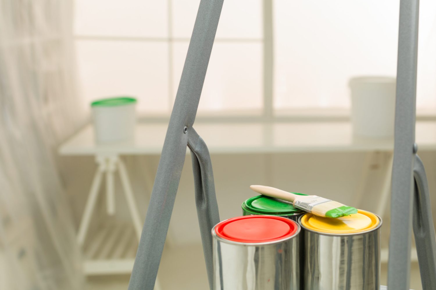 colourful cans of paint on a stepladder window in background ; home improvement concept